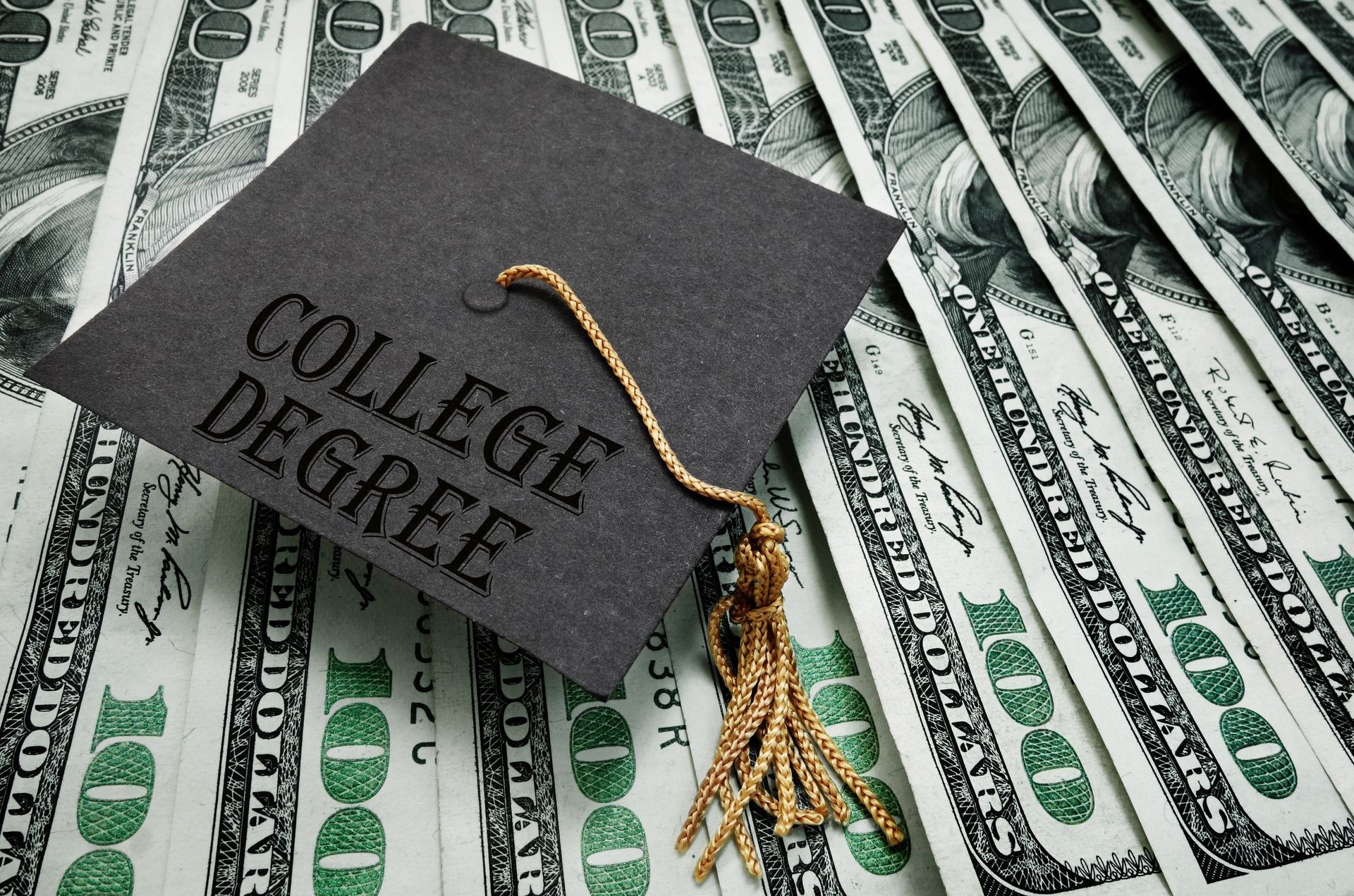 College Degree graduation cap with hundred dollar bills                               
